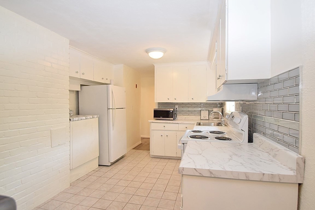 22 Devine Road Randolph, MA 02368 - Photo 10 of 27 a kitchen with a refrigerator a stove top oven and cabinets