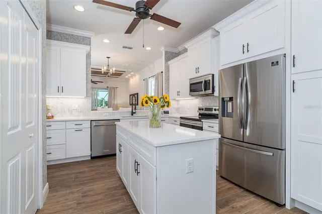 a kitchen with kitchen island granite countertop appliances cabinets a sink and a center island
