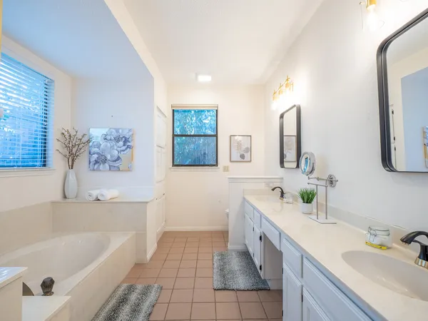 a spacious bathroom with a tub sink and mirror