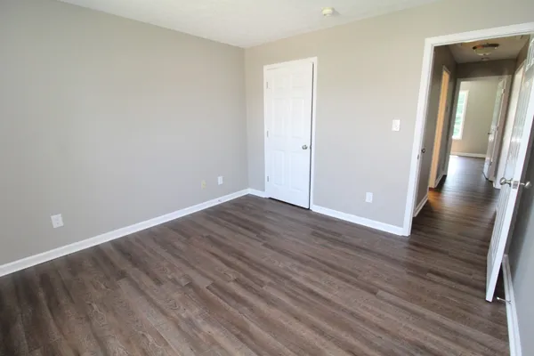 a view of an empty room with wooden floor and a mirror
