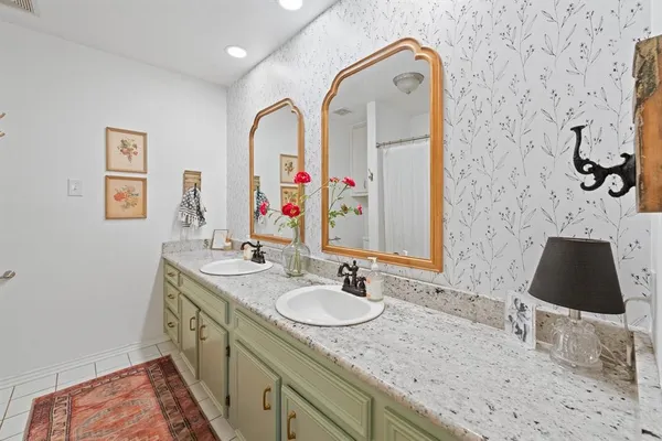 a bathroom with a granite countertop sink a mirror and shower