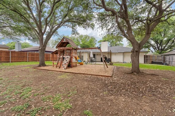 a view of a house with a yard and a large tree