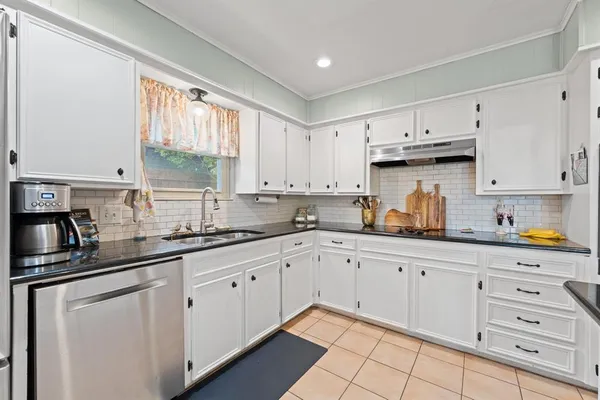 a kitchen with cabinets appliances a sink and a window