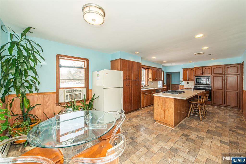 573 Wyckoff Avenue Mahwah, NJ 07430 - Photo 9 of 30 a kitchen with stainless steel appliances granite countertop a refrigerator a sink a stove a dining table and chairs with wooden floor