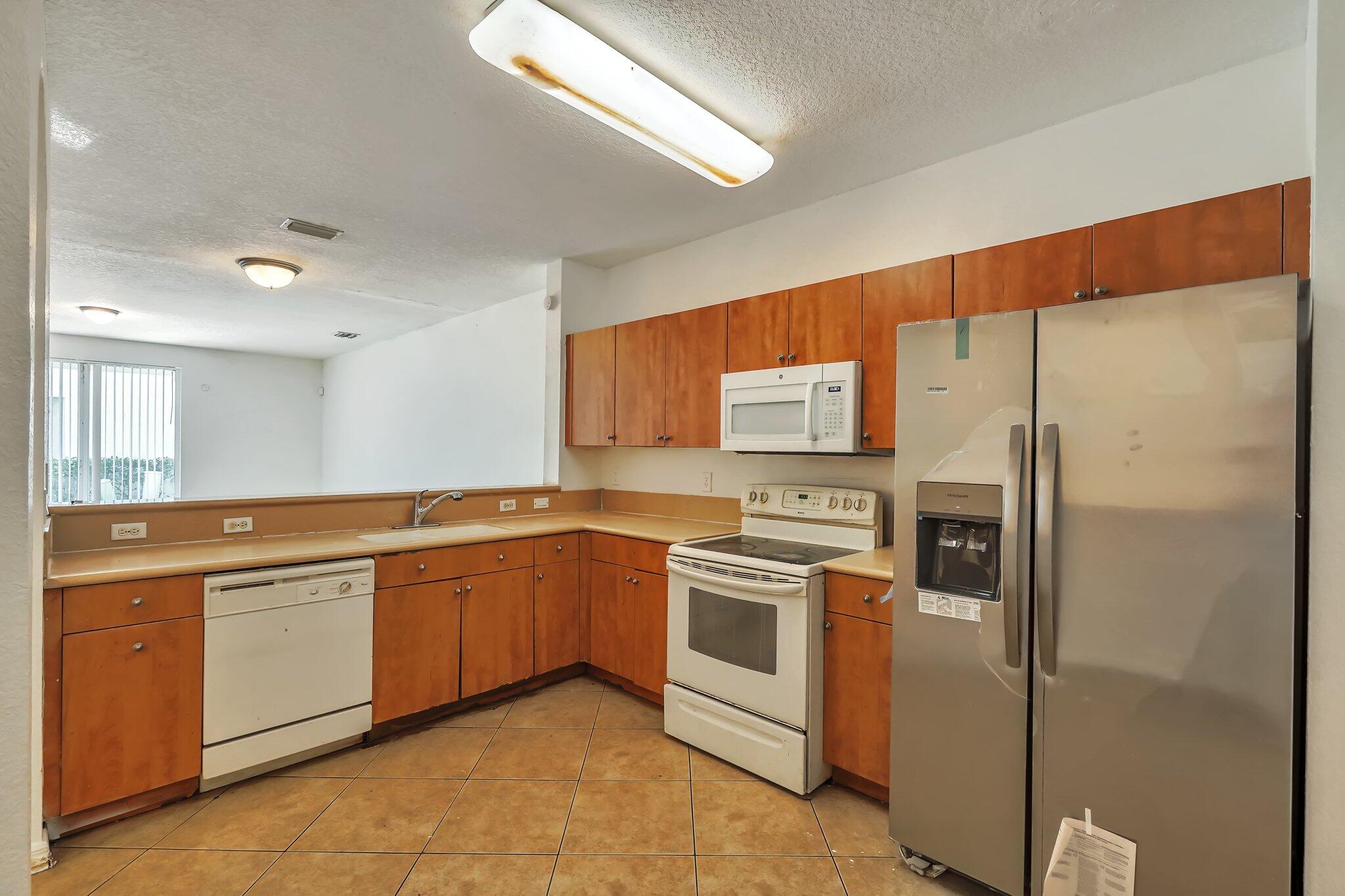 1969 Alamanda Way, Unit 1969 Riviera Beach, FL 33404 - Photo 4 of 26 a kitchen with stainless steel appliances granite countertop a refrigerator and a sink