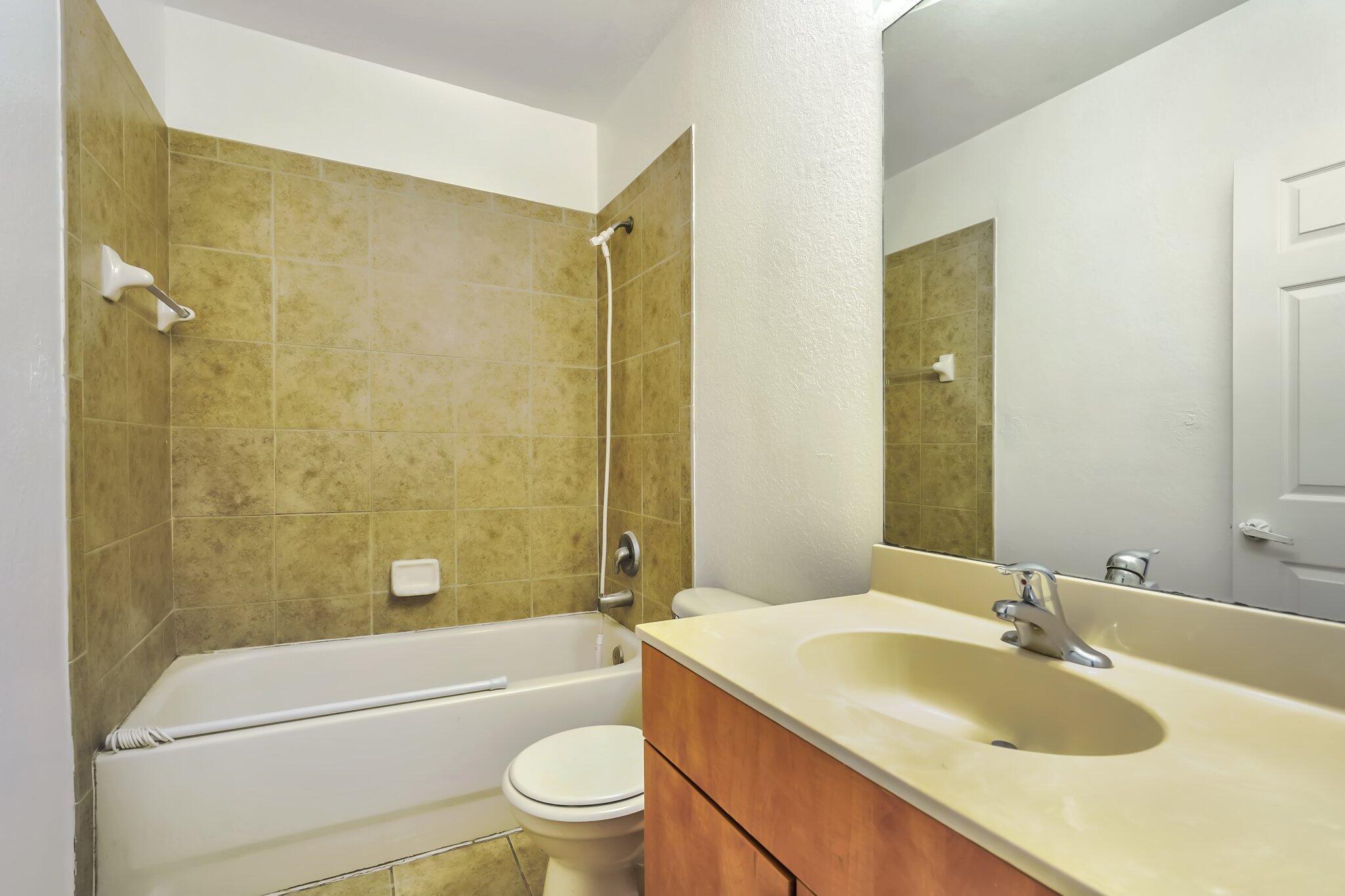 1969 Alamanda Way, Unit 1969 Riviera Beach, FL 33404 - Photo 9 of 26 a bathroom with a granite countertop sink a toilet a mirror a bathtub and shower