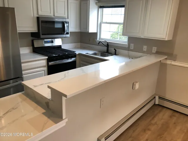 a kitchen with granite countertop a sink a stove top oven a counter space and cabinets
