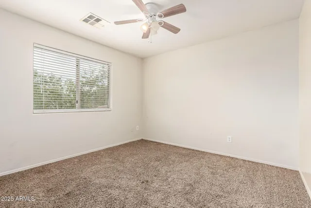 an empty room with a ceiling fan and a window