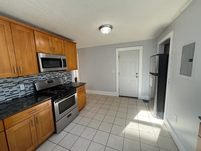 a kitchen with granite countertop a stove a microwave a refrigerator a sink and cabinets