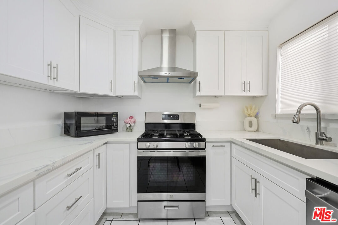 7422 Hazeltine Avenue, Unit 3 Van Nuys, CA 91405 - Photo 10 of 36 a kitchen with white cabinets and appliances