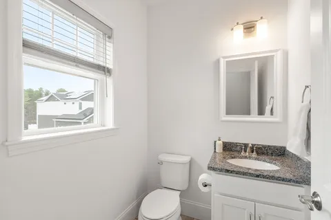 a bathroom with a granite countertop toilet sink and mirror