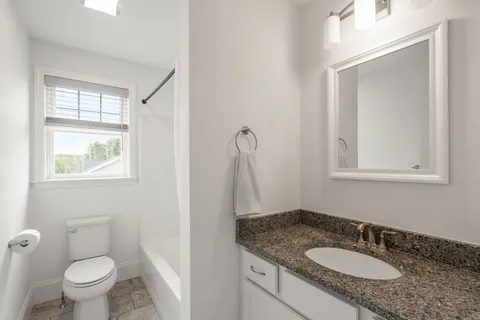 a bathroom with a granite countertop sink toilet and mirror