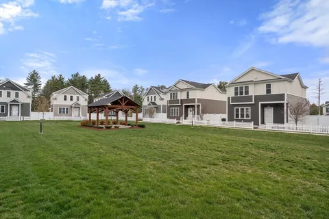 a view of a big house with a big yard and large trees