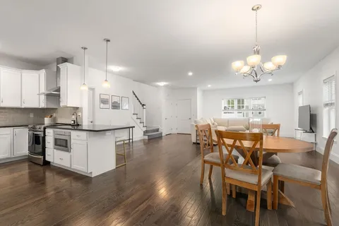 a kitchen with stainless steel appliances a dining table chairs stove and white cabinets