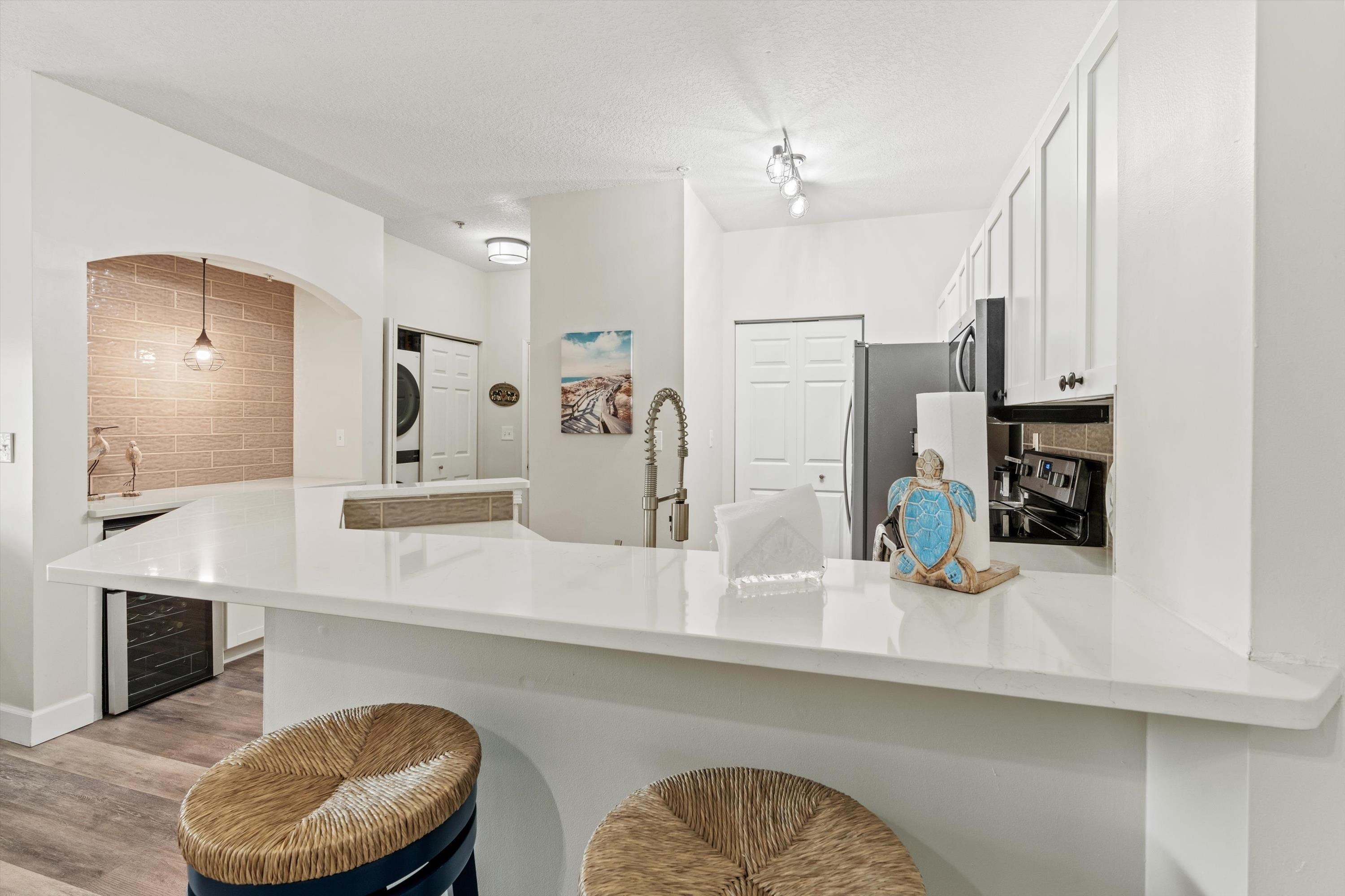 540 Florida Club Boulevard, Unit 210 St. Augustine, FL 32084 - Photo 6 of 33 Kitchen with a peninsula, light wood-style flooring, white cabinets, a breakfast bar, and a textured ceiling