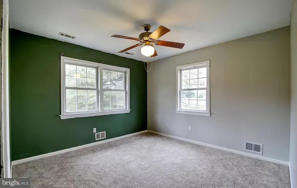 a view of an empty room with window and chandelier fan