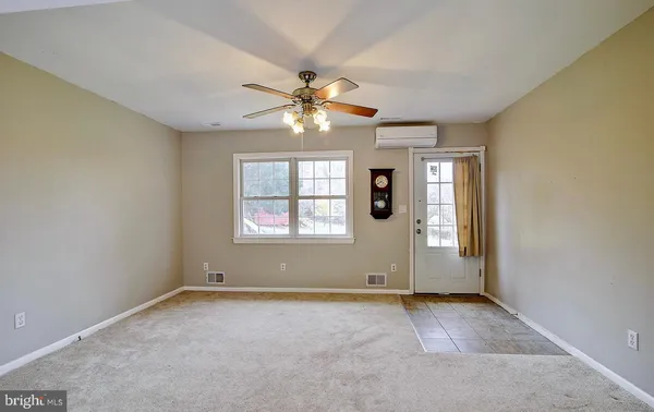 an empty room with chandelier fan and windows