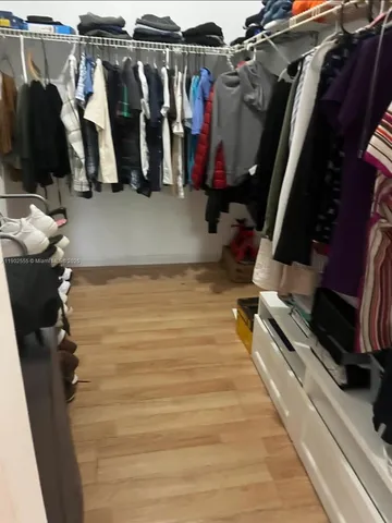 a view of walk in closet with clothes and shoes