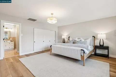 a spacious bedroom with a bed and closet with wooden floor