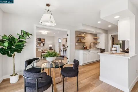 a living room with furniture potted plant and kitchen view