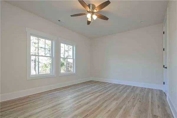 an empty room with wooden floor fan and windows