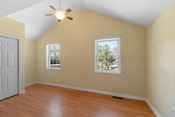 a view of an empty room with a window and wooden floor