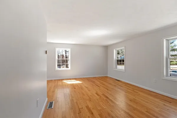 a view of an empty room with a window and wooden floor