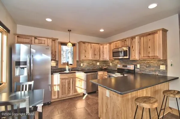 a kitchen with stainless steel appliances granite countertop a refrigerator a stove a sink a dining table and chairs with wooden floor
