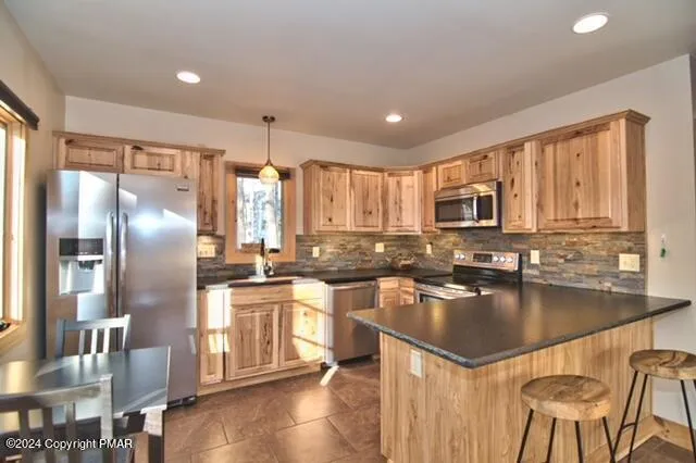 a kitchen with stainless steel appliances granite countertop a refrigerator a stove a sink a dining table and chairs with wooden floor