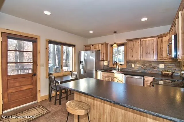 a kitchen with stainless steel appliances granite countertop a stove a sink a dining table and chairs with wooden floor