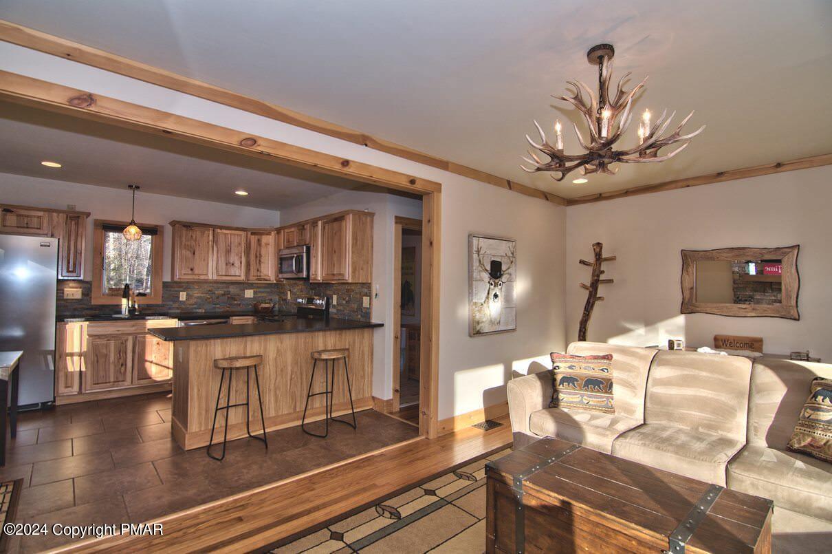 5187 Woodland Avenue Pocono Pines, PA 18350 - Photo 19 of 40 a living room with kitchen island furniture and a chandelier