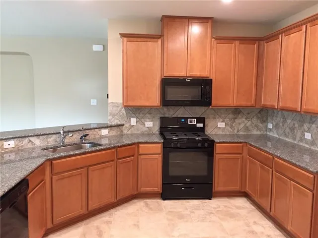 a kitchen with stainless steel appliances granite countertop a stove sink and cabinets