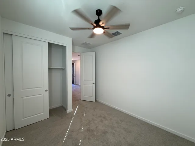 an empty room with closet and fan
