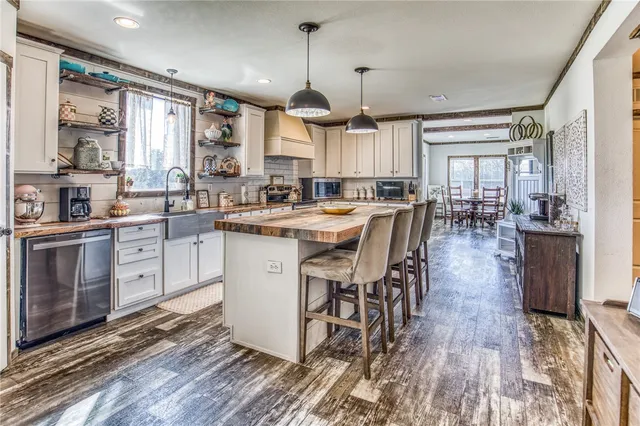 a kitchen with stainless steel appliances kitchen island granite countertop a stove refrigerator and cabinets