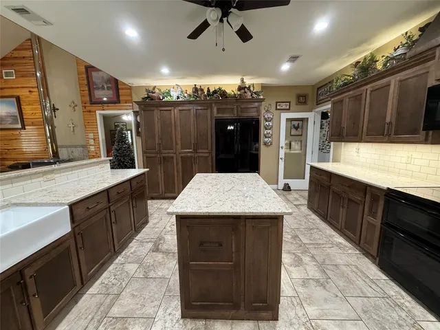 a large kitchen with a large counter top stainless steel appliances and cabinets