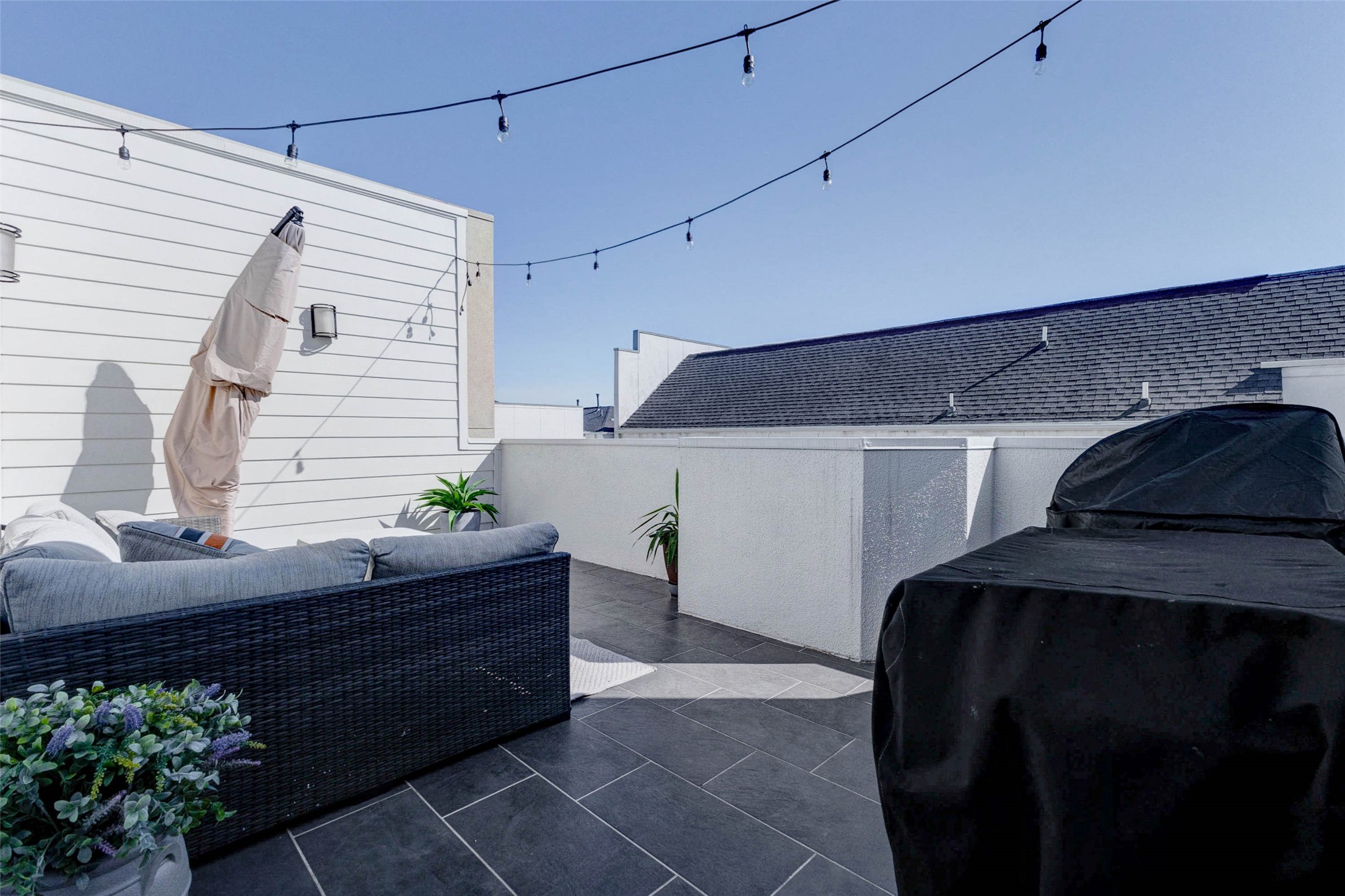 5715 Larkin Street, Unit D Houston, TX 77007 - Photo 27 of 38 Expansive rooftop terrace offering multiple zones for entertaining, including outdoor seating and grilling area. String lights stretch overhead, creating a warm evening atmosphere. High privacy walls provide seclusion while still allowing open sky views, perfect for relaxing or hosting friends.