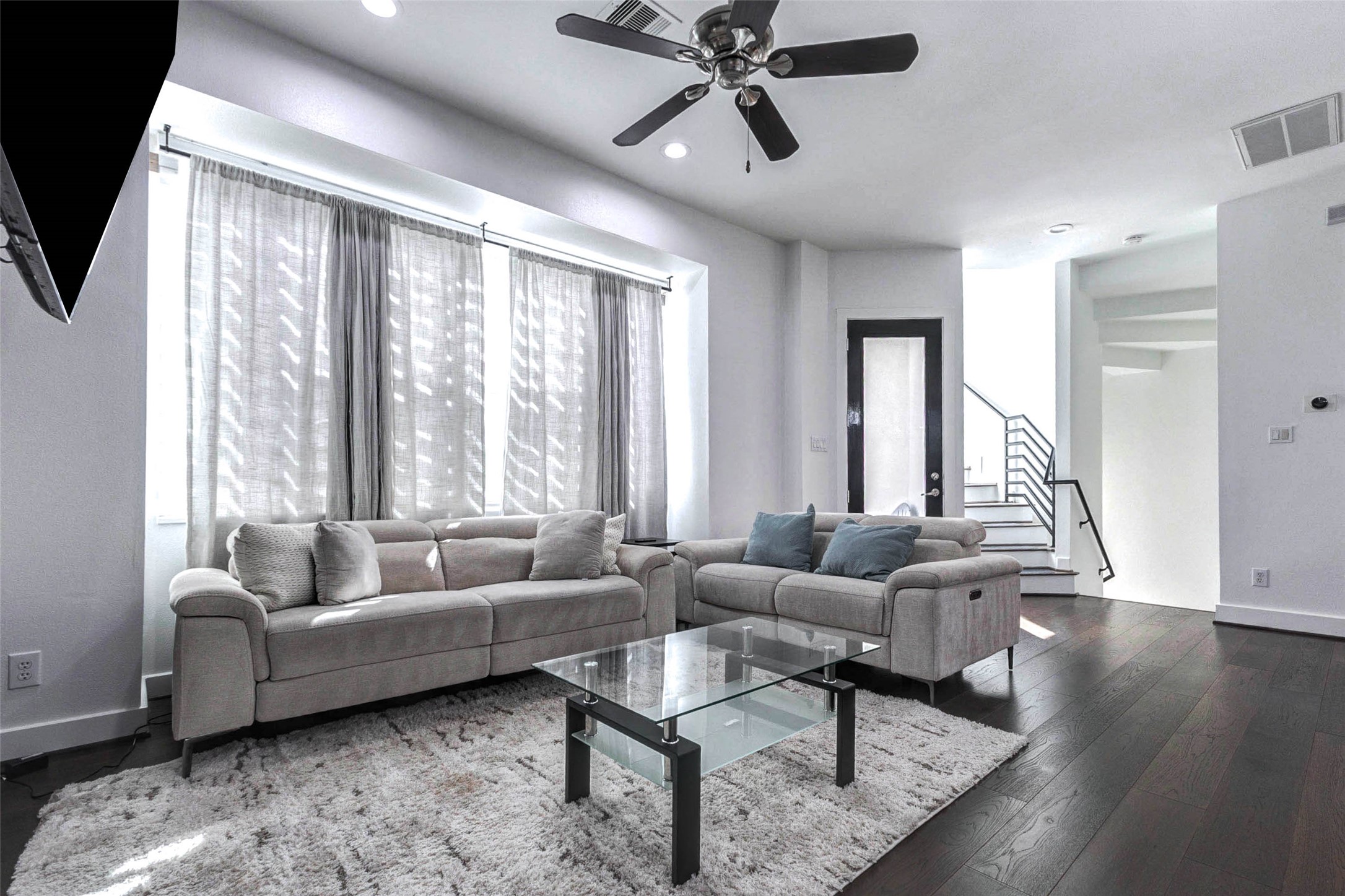 5715 Larkin Street, Unit D Houston, TX 77007 - Photo 3 of 38 Bright second floor living room anchored by large windows dressed with soft drapery, allowing natural light to fill the space. Ceiling fan and recessed lighting provide both comfort and style.