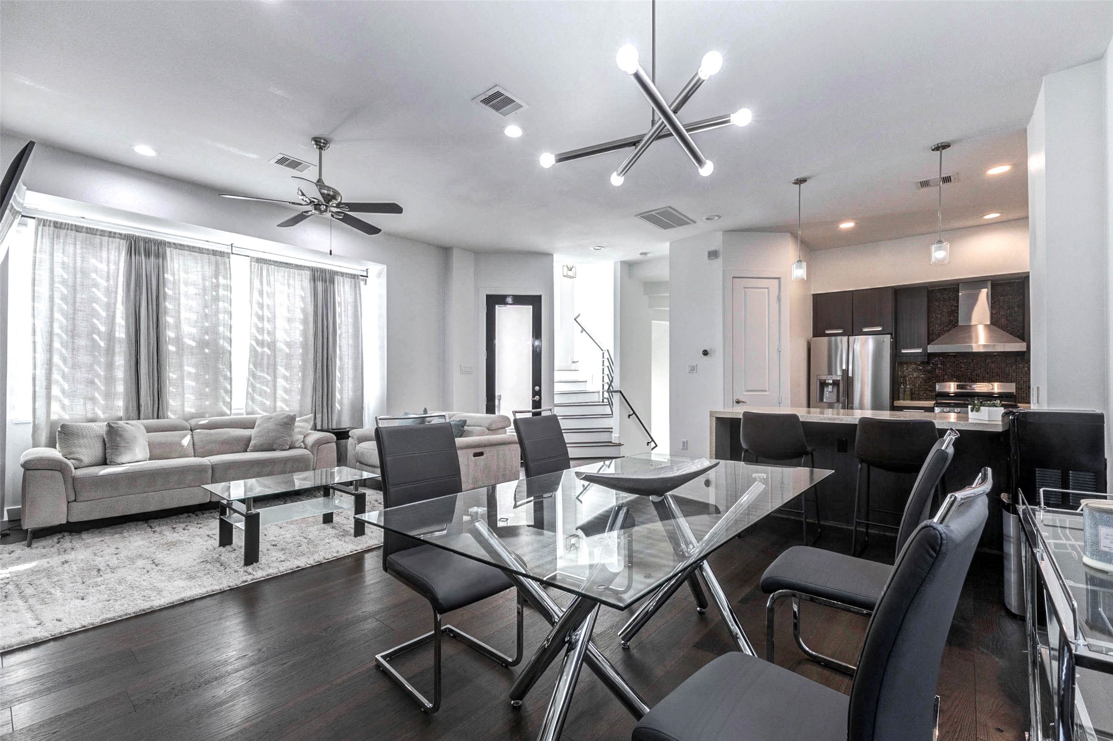 5715 Larkin Street, Unit D Houston, TX 77007 - Photo 5 of 38 Dining area with contemporary glass display cabinets that add sophistication and storage for décor or collectibles. A large wall mirror enhances depth and reflects light, making the space feel even more expansive. Clean lines and modern finishes complement the home’s overall aesthetic.