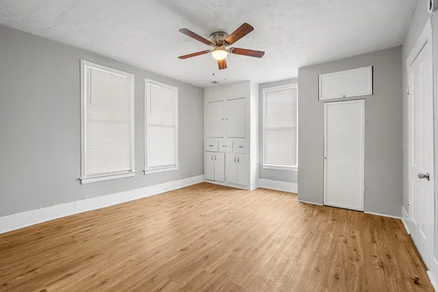 an empty room with wooden floor and ceiling fan