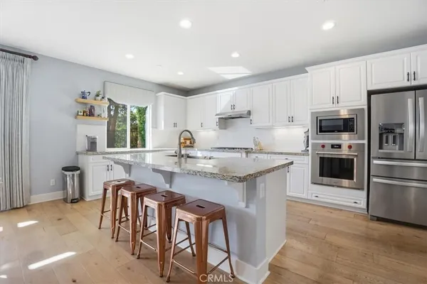 a kitchen with granite countertop a table chairs microwave and refrigerator