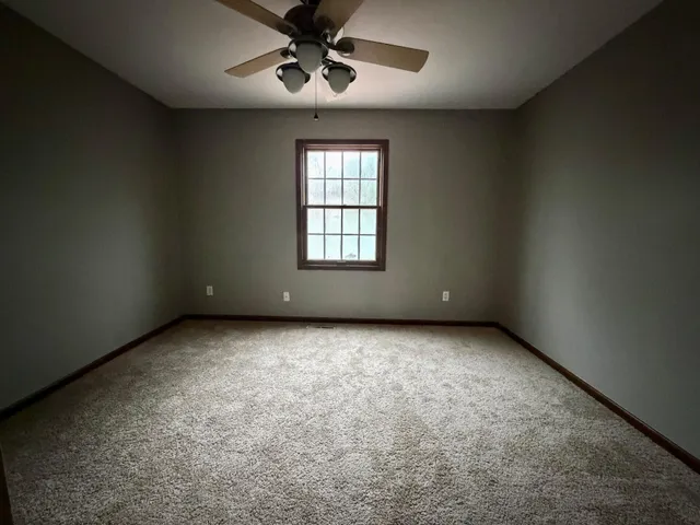 an empty room with a window and a fan