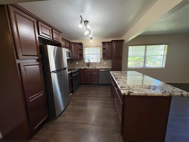 a kitchen with granite countertop stainless steel appliances a refrigerator microwave and sink