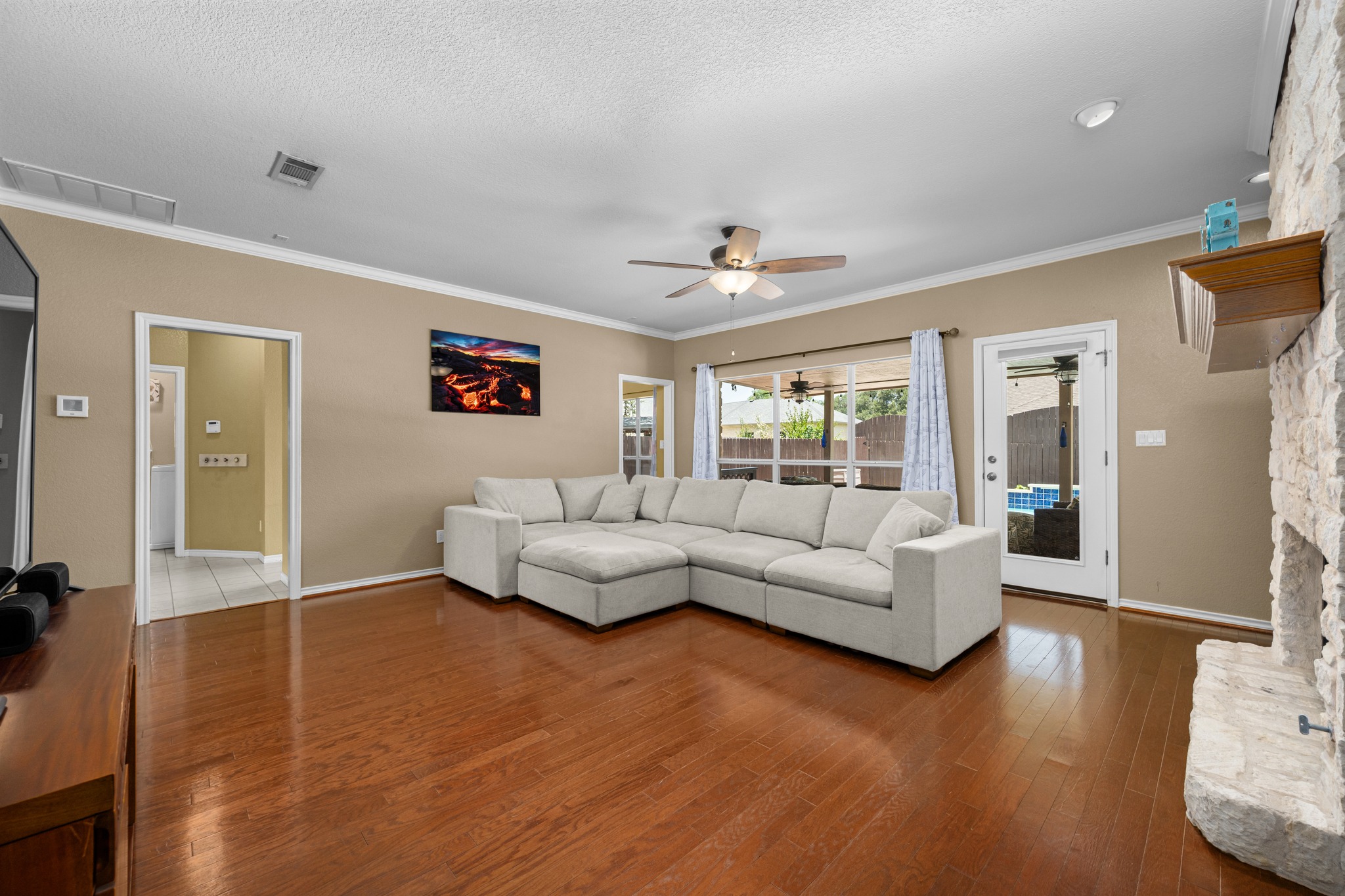 108 Thornwood Road Georgetown, TX 78628 - Photo 9 of 40 Luminous living area features gleaming hardwood floors and a stone fireplace, perfect for gatherings.