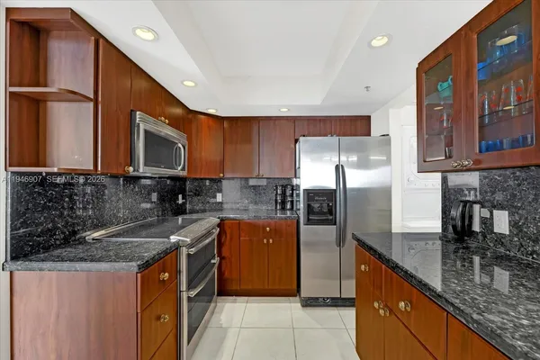 a kitchen with stainless steel appliances granite countertop a sink stove microwave and refrigerator