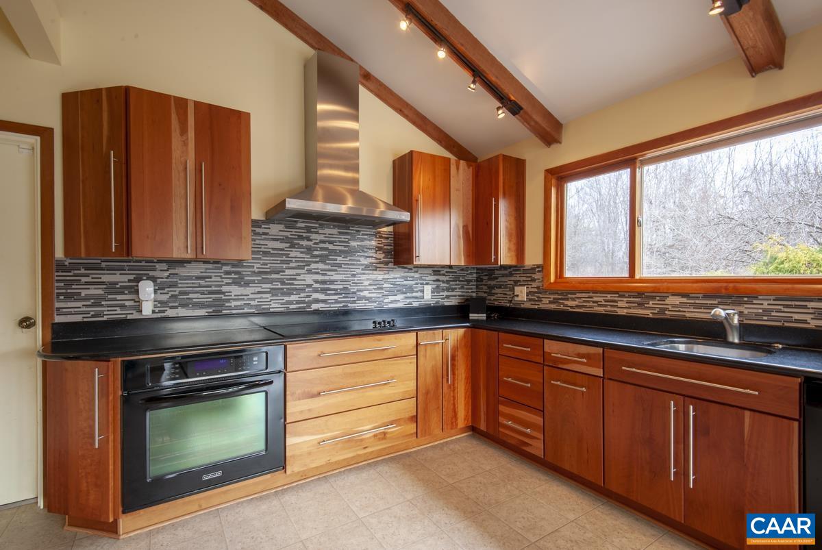 397 Rodes Valley Drive Nellysford, VA 22958 - Photo 12 of 46 a kitchen with granite countertop wooden cabinets stainless steel appliances and a large window