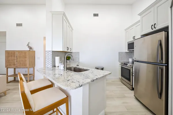 a kitchen with stainless steel appliances granite countertop a refrigerator a stove and a dining table