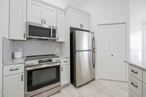 a kitchen with white cabinets and stainless steel appliances