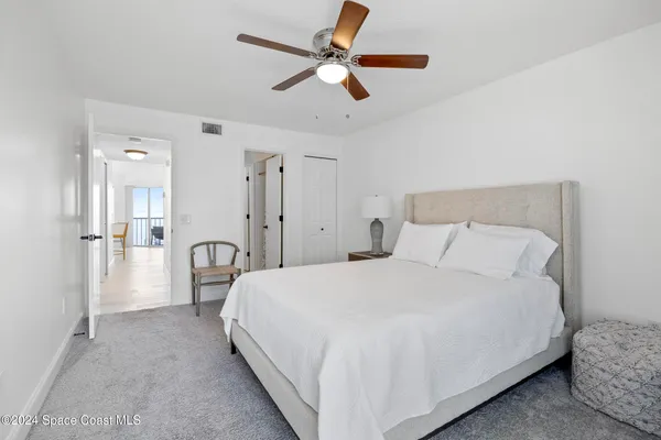 a bedroom with a bed ceiling fan and a wooden floor
