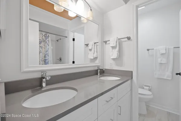 a bathroom with a granite countertop sink a toilet and a mirror