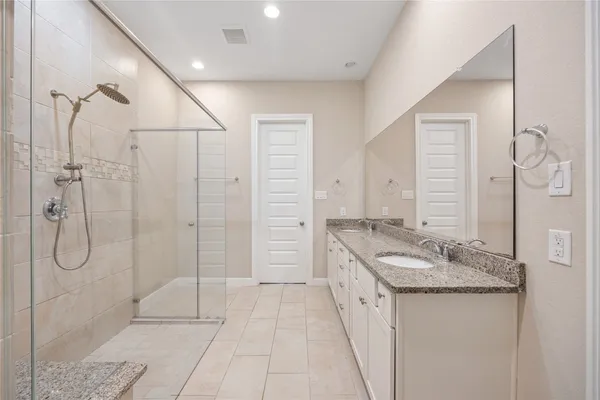 a spacious bathroom with a granite countertop sink a mirror and a shower
